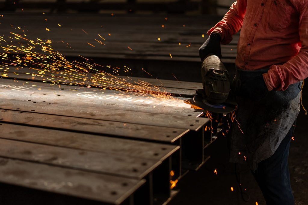 Operator grinding a steel beam, sparks visible